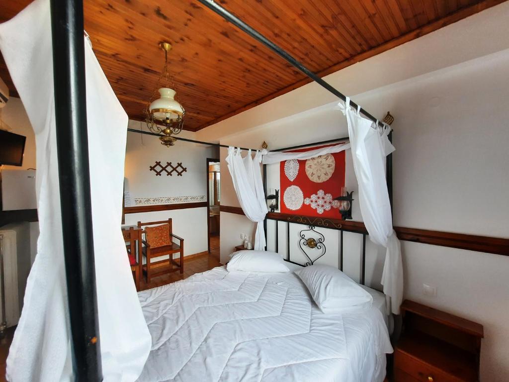 sypialnia z białym łóżkiem i drewnianym sufitem w obiekcie Αρχοντικό Κονάκι- Konaki Pelion w mieście Tsagarada