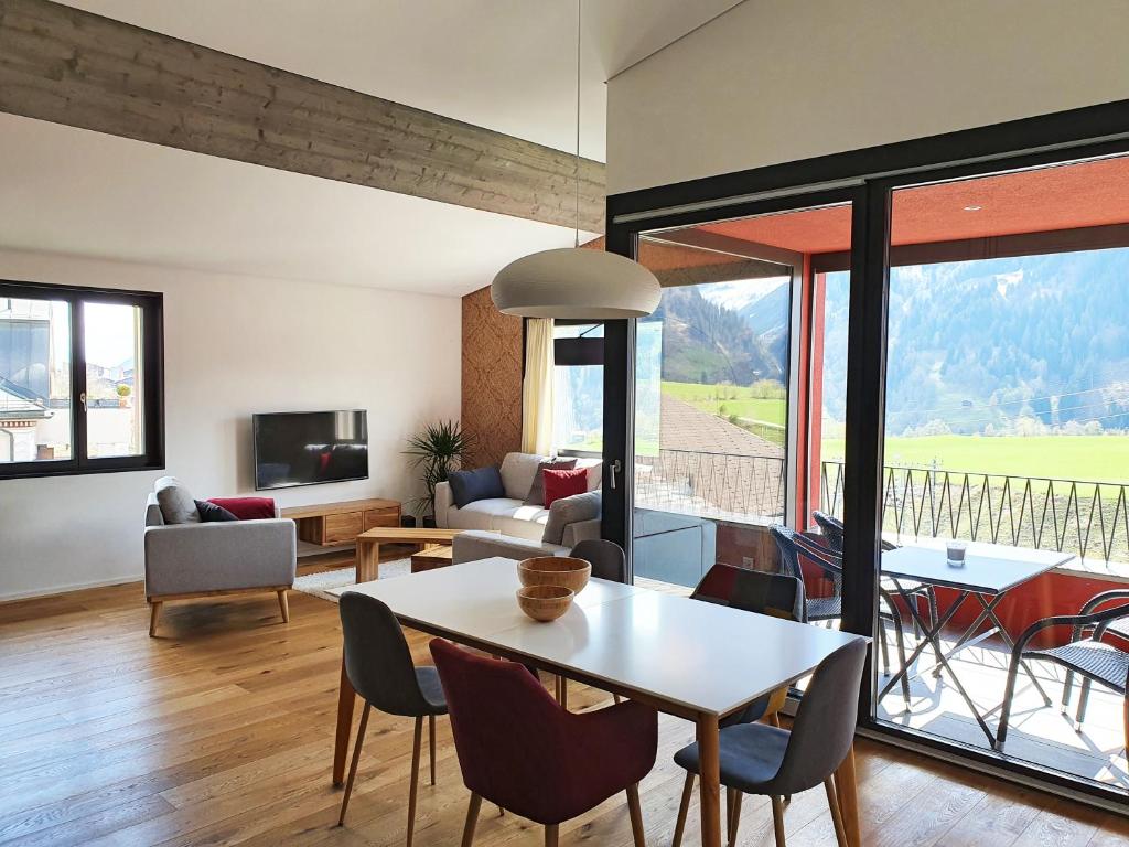 een woonkamer met een tafel en stoelen bij 3,5 Zimmer Dachwohnung: Modern, komfortabel, zentral, mit Bergsicht in Disentis