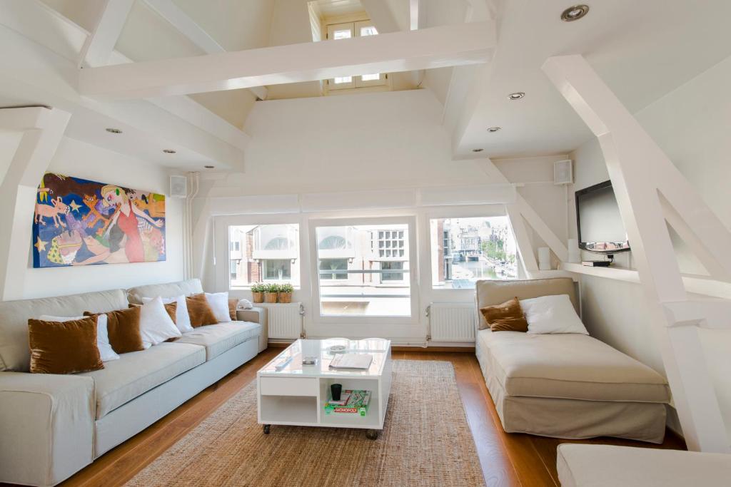a white living room with white couches and a table at The Catch Apartment in Amsterdam