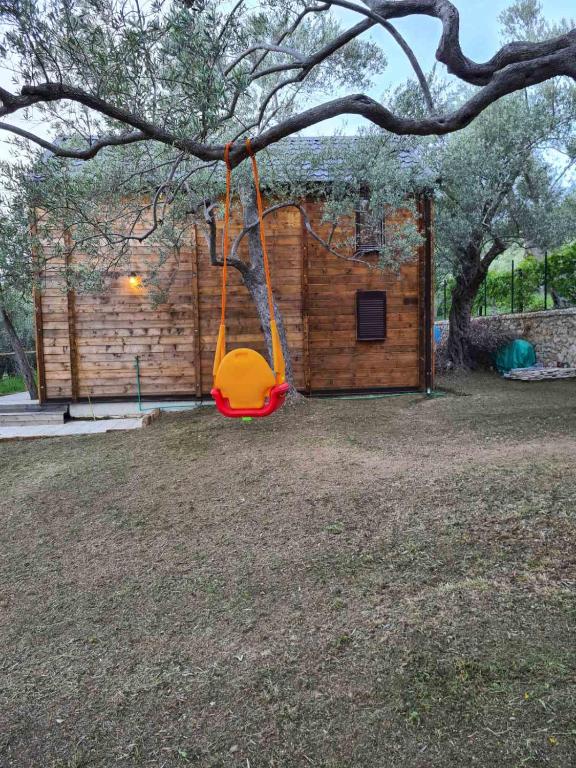 a swing hanging from a tree in front of a house at OLEA COTTAGE in Ulcinj