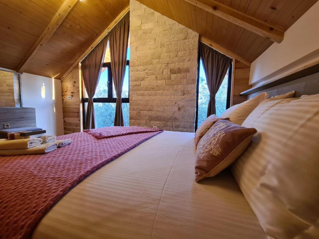 a large bed in a room with windows at OLEA COTTAGE in Ulcinj