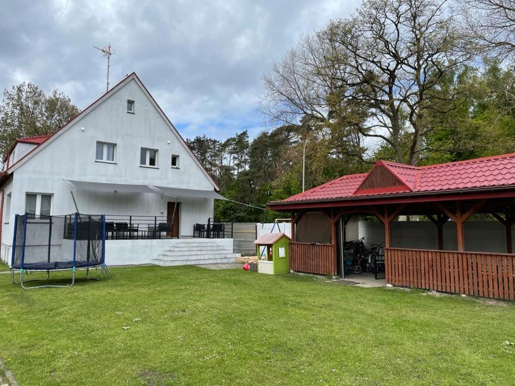 a white house with a red roof and a yard at Zacisze Nest - noclegi blisko plaży in Mielno