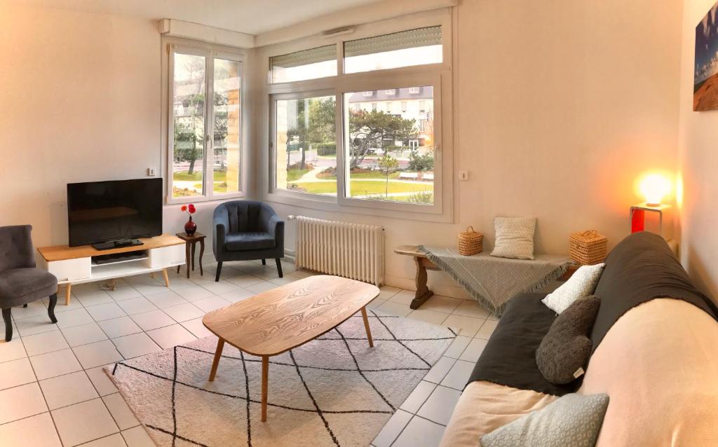sala de estar con sofá y TV en Les Alisés, en Merville-Franceville-Plage