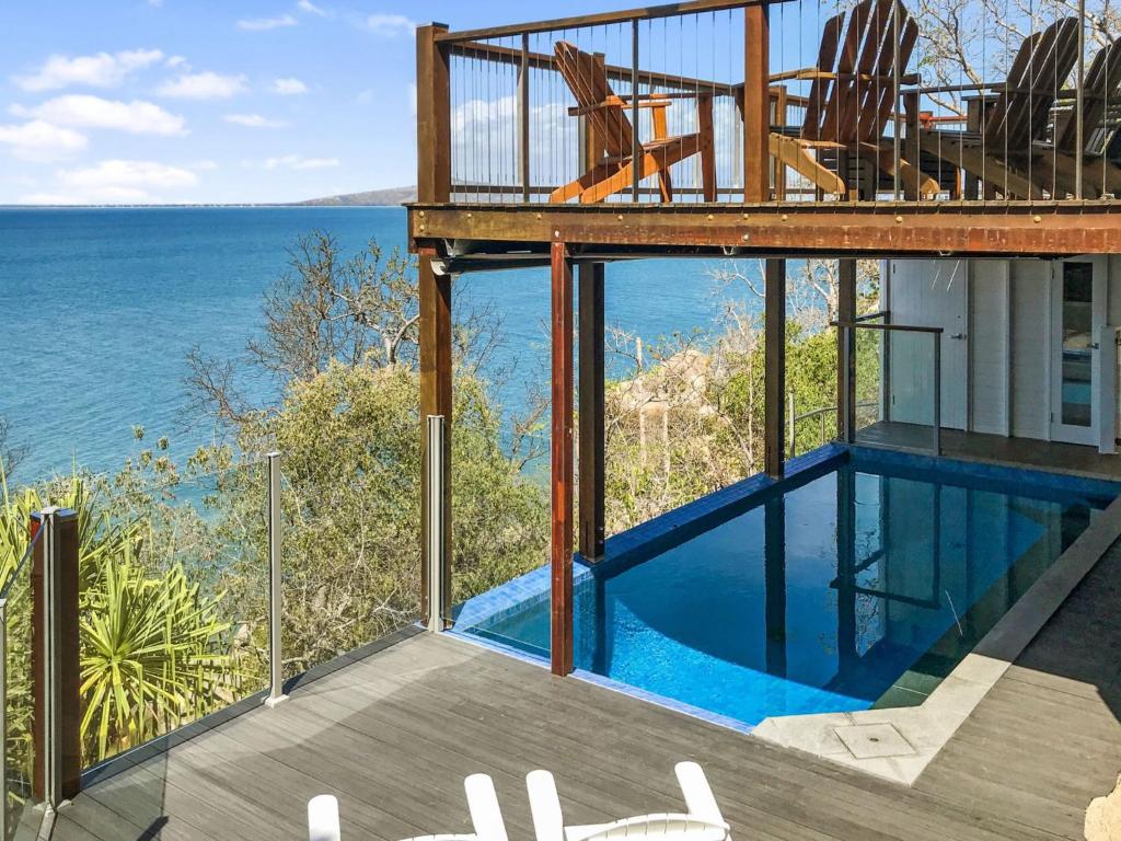 a house with a swimming pool and a view of the ocean at Driftwood in Picnic Bay