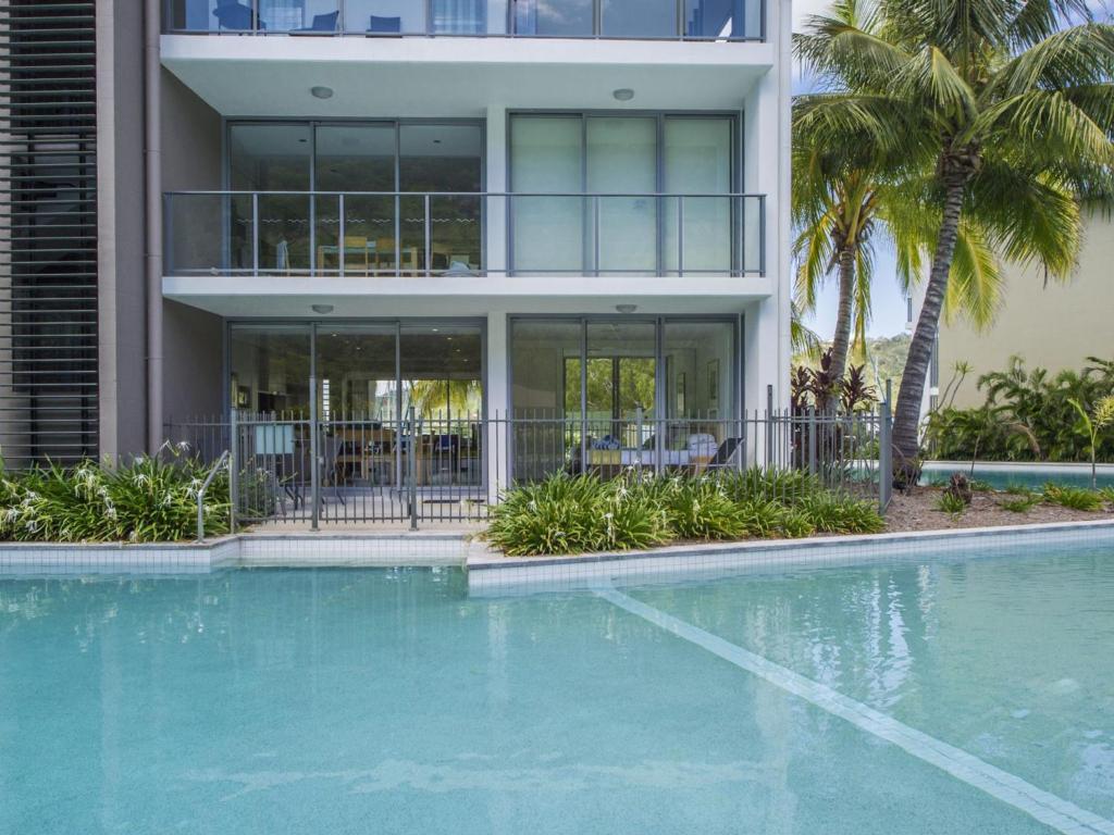 a house with a swimming pool in front of a building at Blue on Blue Apartment 1011 in Nelly Bay