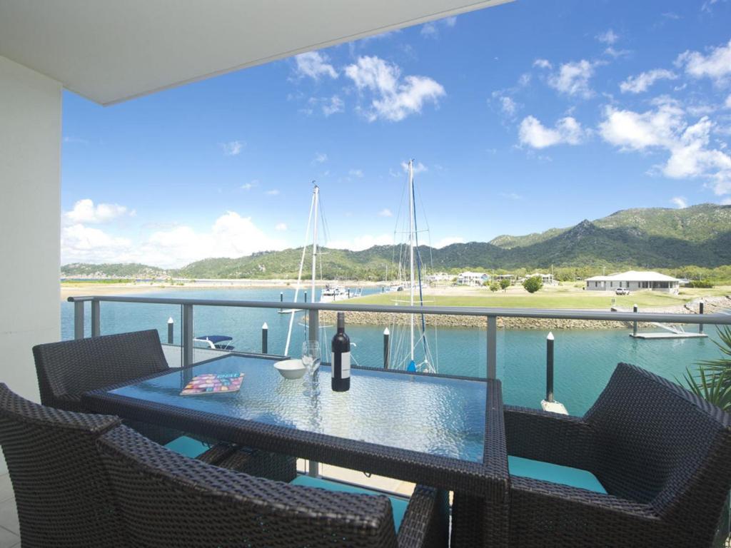 a table and chairs on a balcony with a view of the water at Blue on Blue Superior Studio Room 1241 in Nelly Bay