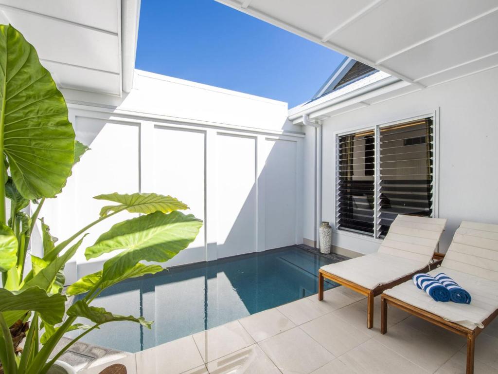 una piscina cubierta en una casa con muebles y plantas blancos en Reflections Emerald Villa 1, en Picnic Bay
