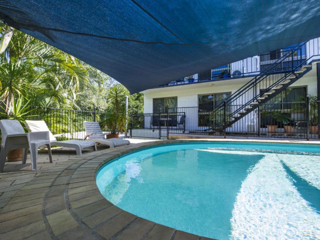 a swimming pool with a blue umbrella next to a house at Magnetic North Apartment 1 in Arcadia