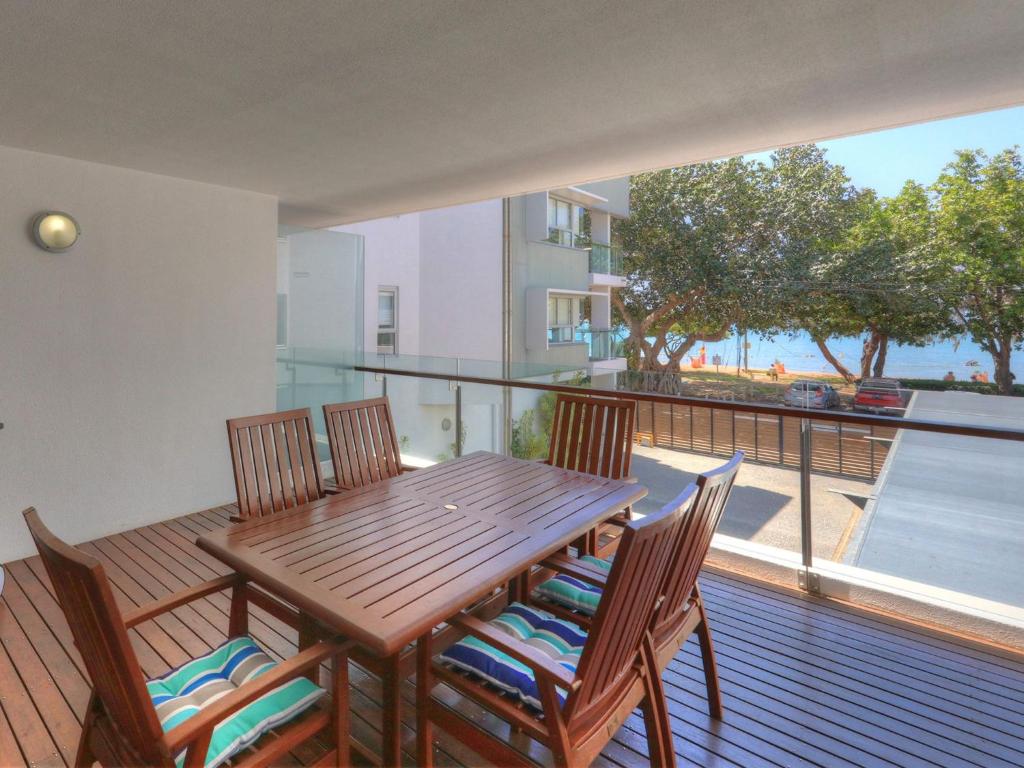 a wooden table and chairs on a balcony with a view at Maggies Beachfront Apartment 7 in Horseshoe Bay