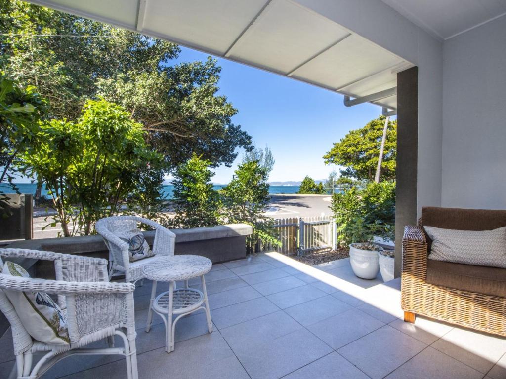 een patio met een tafel en stoelen en uitzicht op de oceaan bij Reflections Topaz Villa 2 in Picnic Bay
