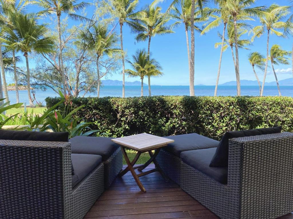 un patio con 2 sillas, una mesa y palmeras en Pure Magnetic Villa 1, en Nelly Bay