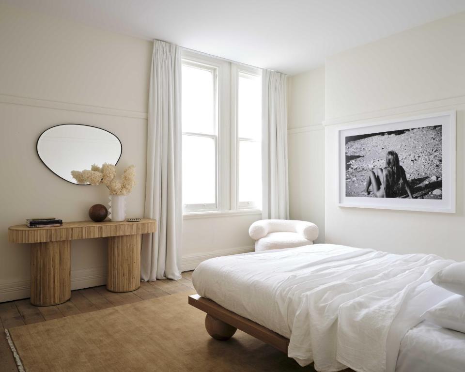 een slaapkamer met een bed, een stoel en een spiegel bij Three Rooms Sydney in Sydney
