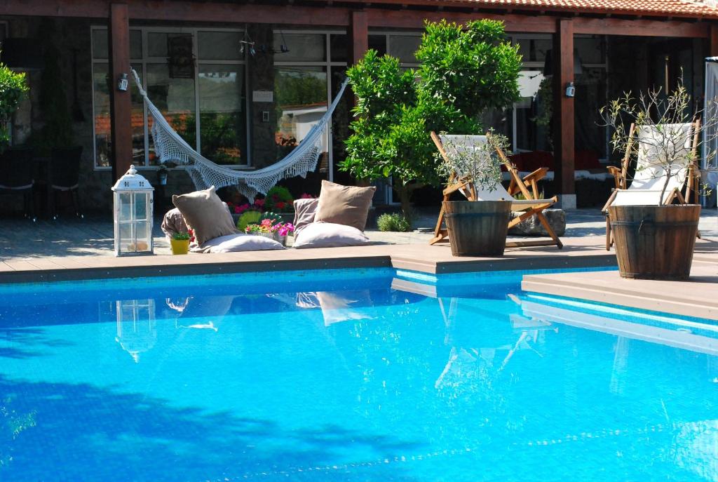 een zwembad met stoelen en een hangmat naast een gebouw bij Casa Relogio de Sol in Lamego