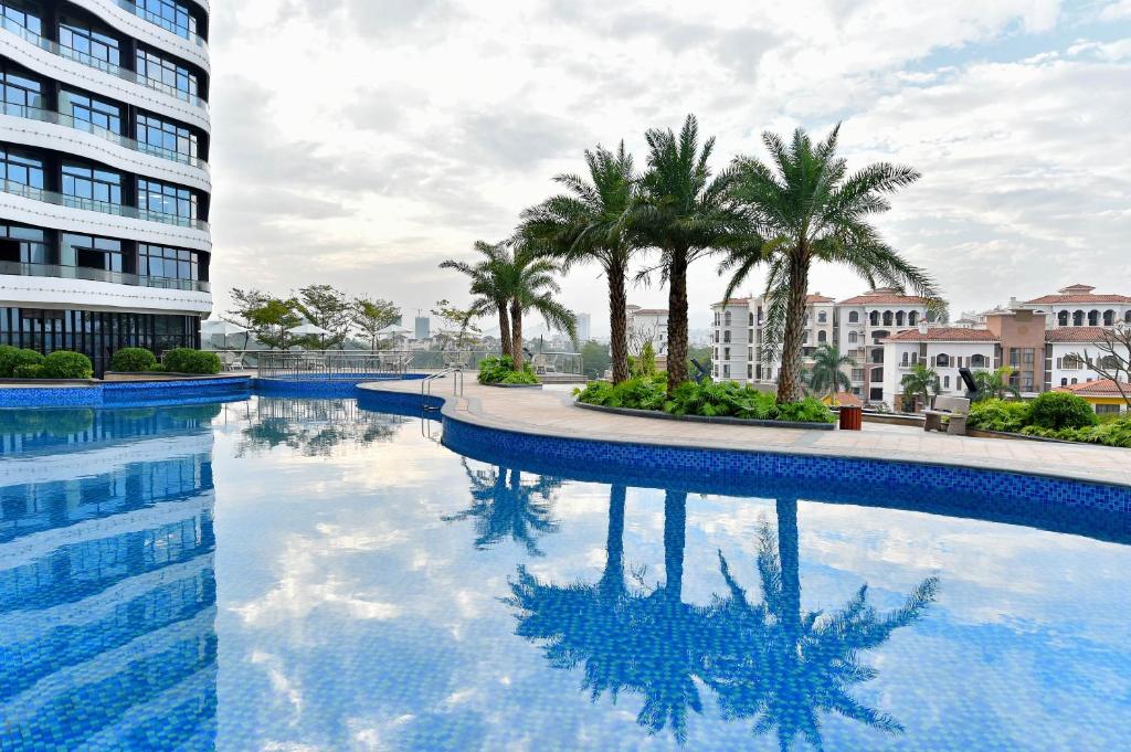 una piscina con palmeras y un edificio en Grand Skylight International Hotel Huizhou, en Huizhou