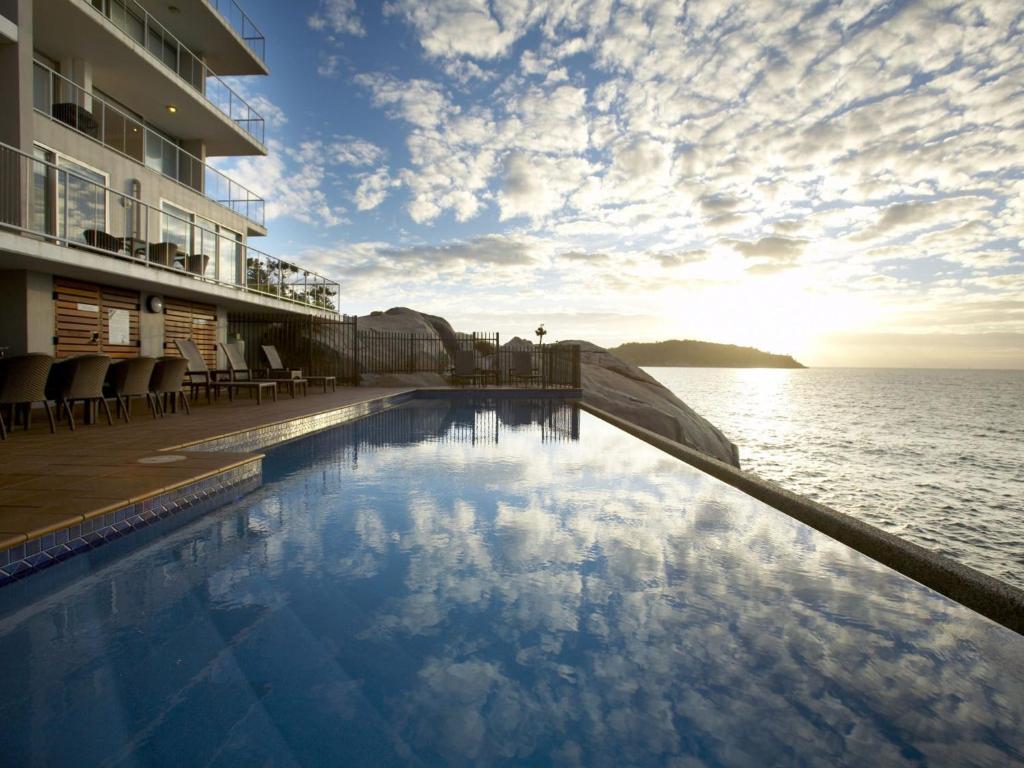 a swimming pool on the side of a building next to the ocean at 1 Bright Point Apartment 5201 in Nelly Bay