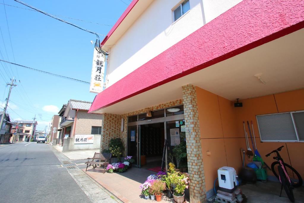 un bâtiment avec un toit rose dans une rue dans l'établissement kangetsusou, à Unzen