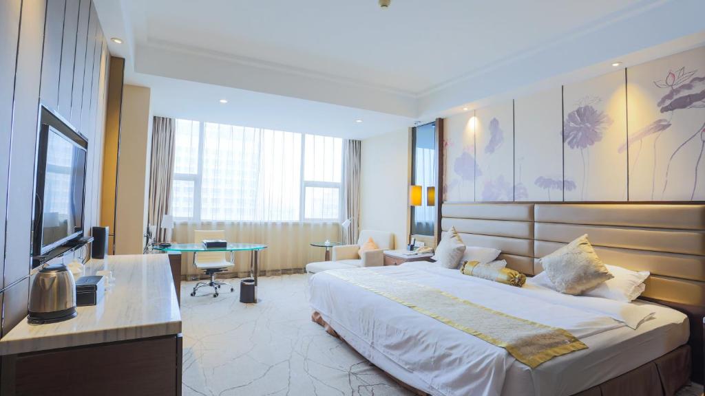 una camera d'albergo con un letto grande e una scrivania di Huai'an Jinling Hotel a Huai'an