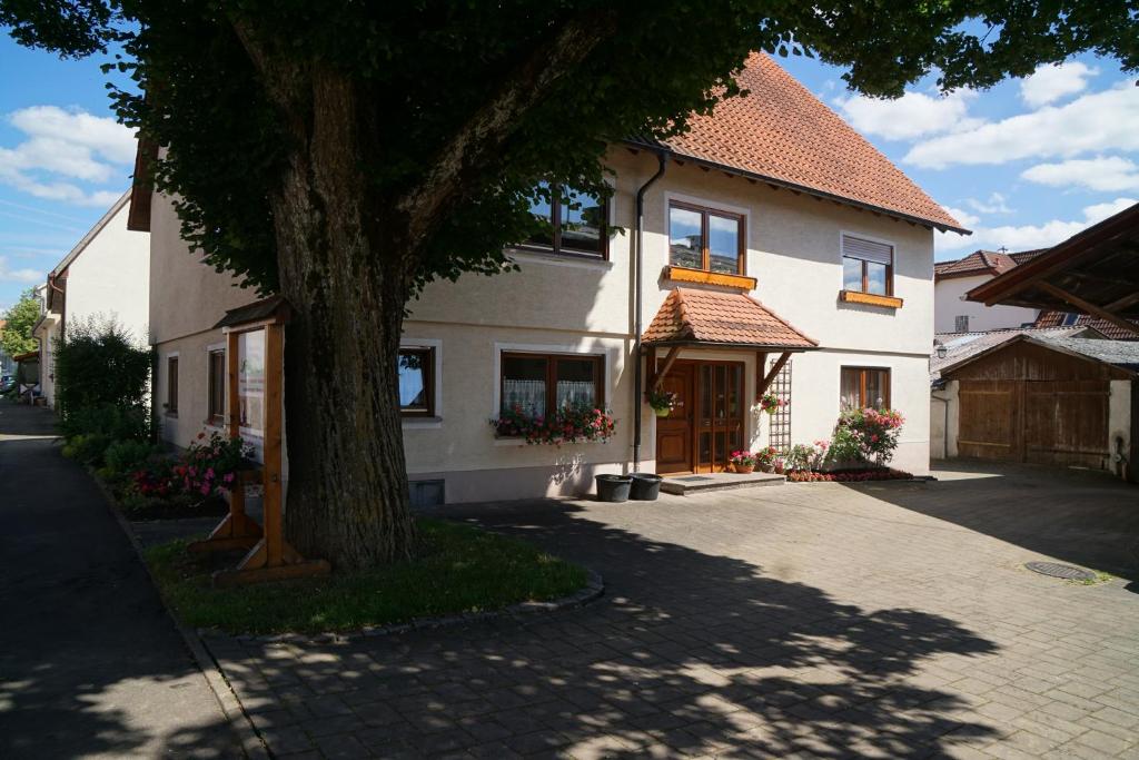 ein großes weißes Haus mit einem Baum davor in der Unterkunft Ferienwohnungen Hof Heinzmann in Kohlstetten