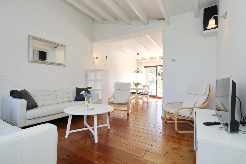 uma sala de estar com um sofá e uma mesa em Holiday home het Zeepaardje em Noordwijkerhout