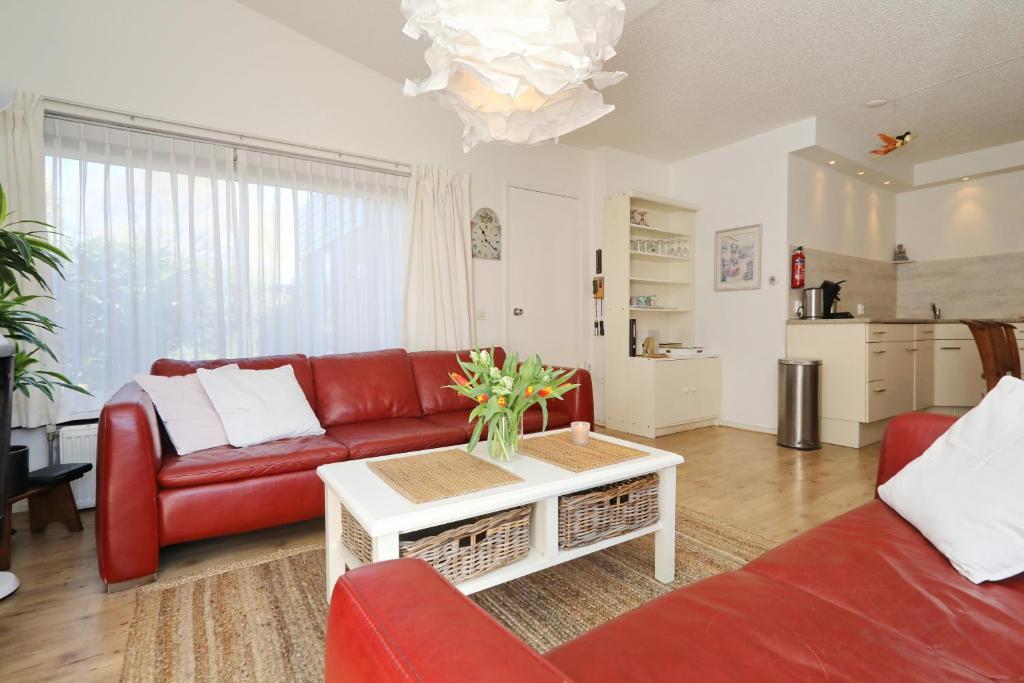 uma sala de estar com um sofá vermelho e uma mesa em Holiday home de Zeester em Noordwijkerhout