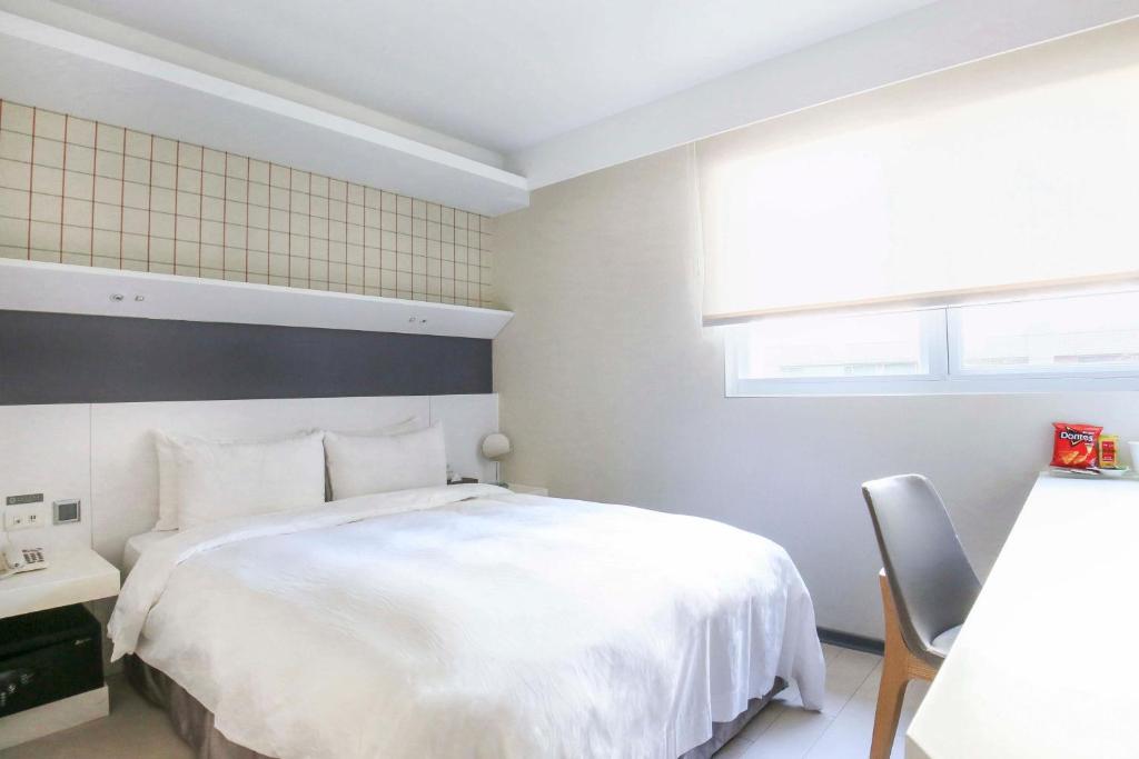 a bedroom with a white bed and a chair at Dandy Hotel - Tianmu Branch in Taipei