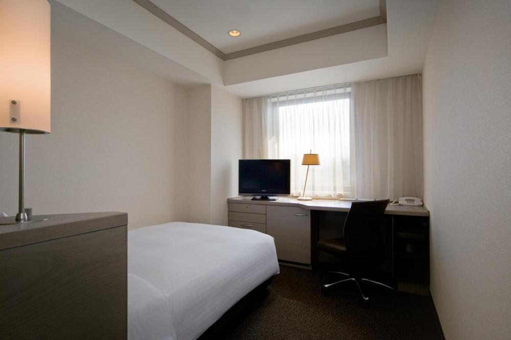 a hotel room with a bed and a desk with a computer at Hotel Nikko Fukuoka in Fukuoka