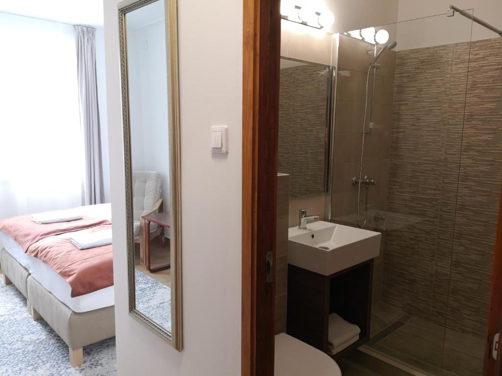 a bathroom with a sink and a shower and a bed at Laguna Panzió in Gárdony