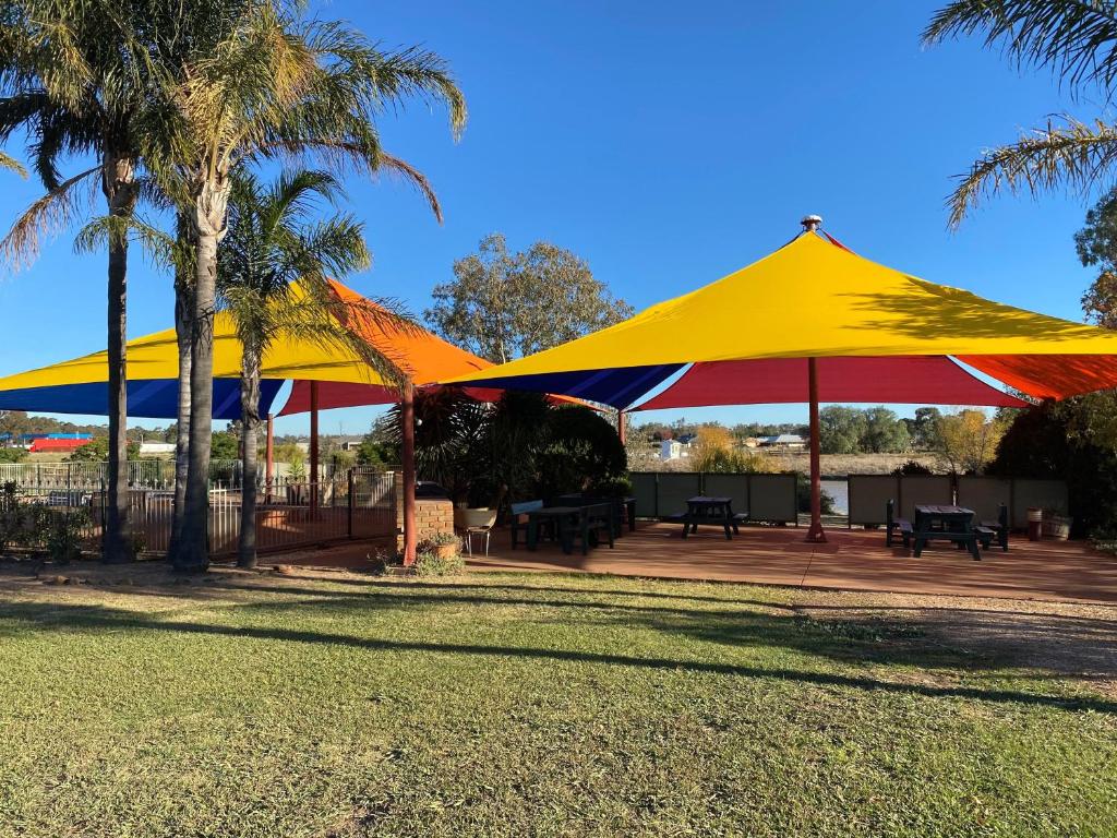 two large yellow and red umbrellas in a park at Paradise Lakes Motel Shepparton in Shepparton