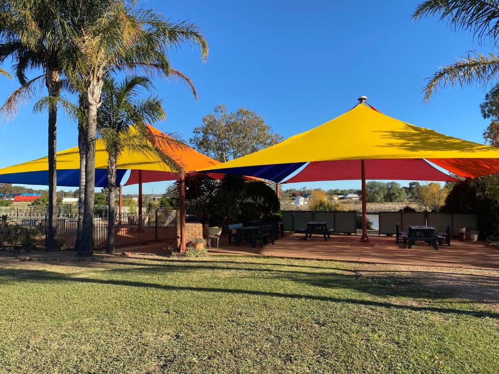 Deux grands parapluies jaunes et rouges dans un parc dans l'établissement Paradise Lakes Motel Shepparton, à Shepparton