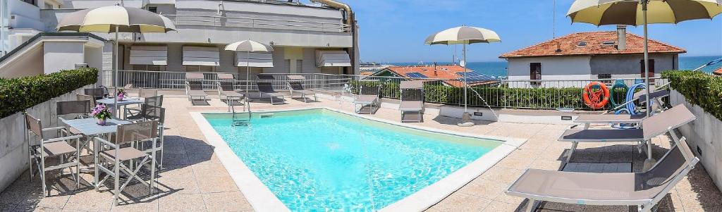 a swimming pool with chairs and umbrellas next to a building at Hotel Corallo in Fano
