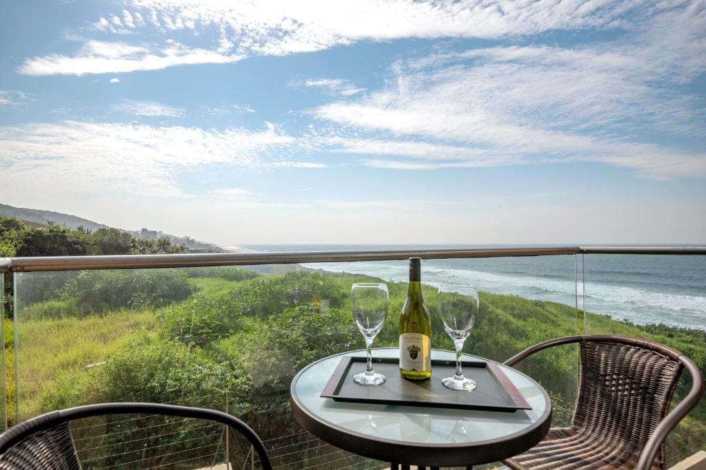 a table with two wine glasses sitting on a balcony at Sea De La Vie 25 by HostAgents in La Mercy
