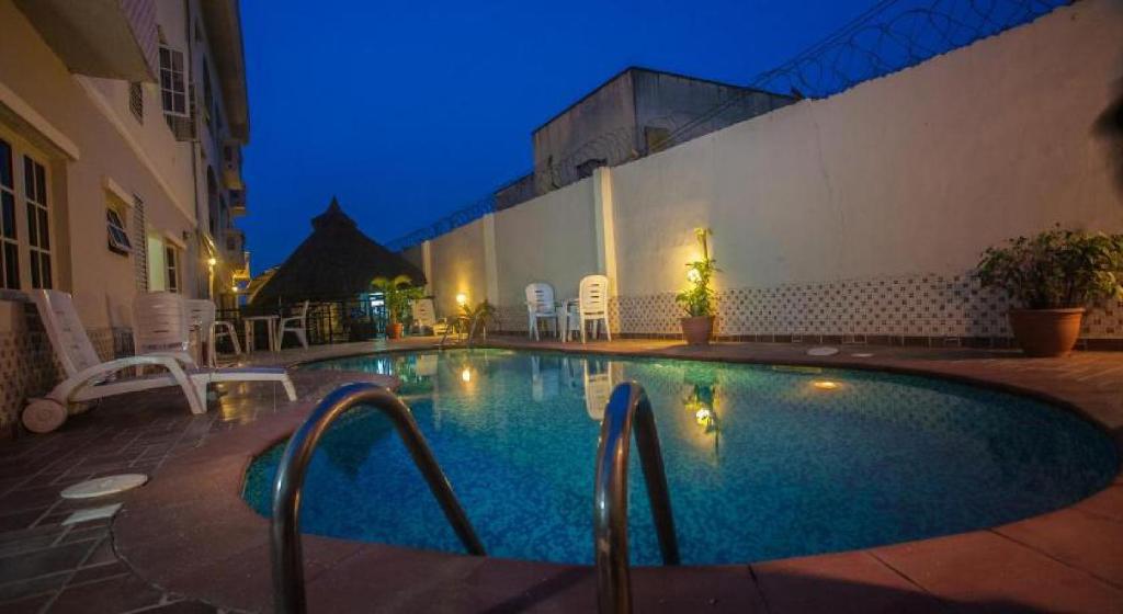 a swimming pool at night with chairs and a building at Apartment Royale Hotel-2 Bd Apartment in Ikeja