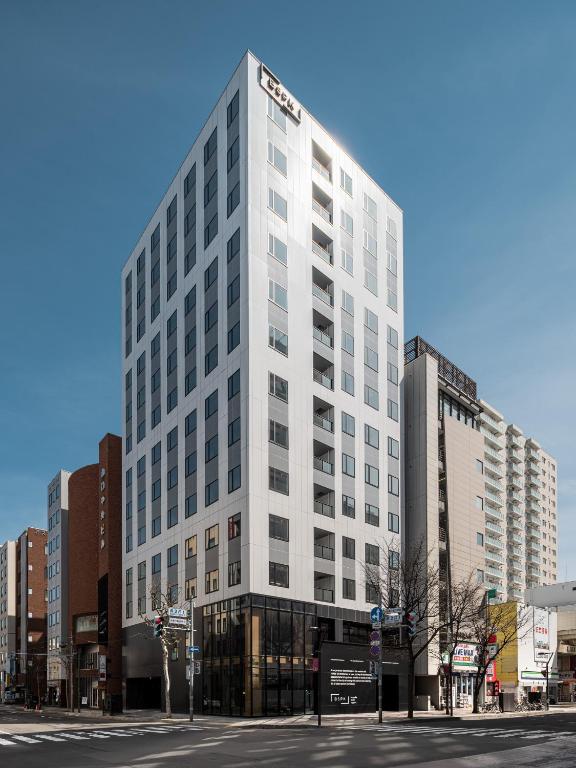 a tall white building on a city street at Bespoke Hotel Sapporo in Sapporo