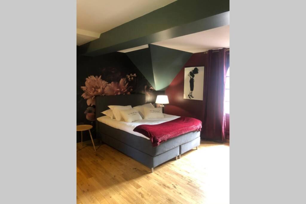 een slaapkamer met een bed met een rode deken bij L’annexe du Manoir in Gauciel