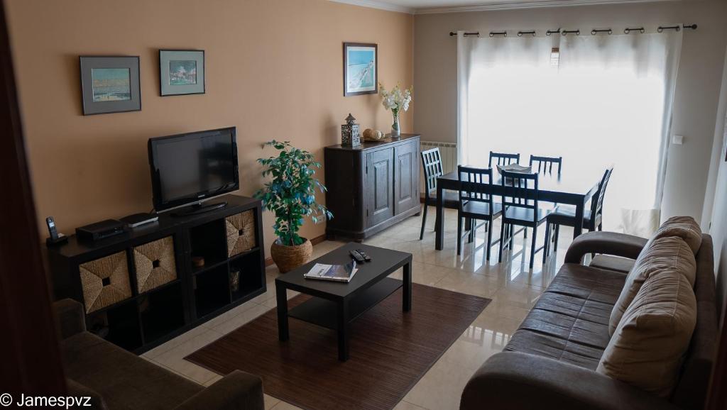 a living room with a couch and a tv and a table at Apartamento Santos Graça in Póvoa de Varzim