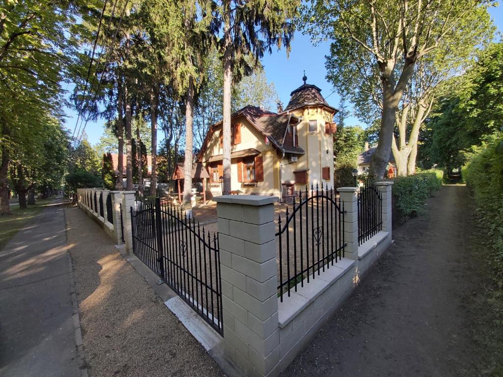 a fence in front of a house with a building at Balatonszemesi Nyaralóház in Balatonszemes