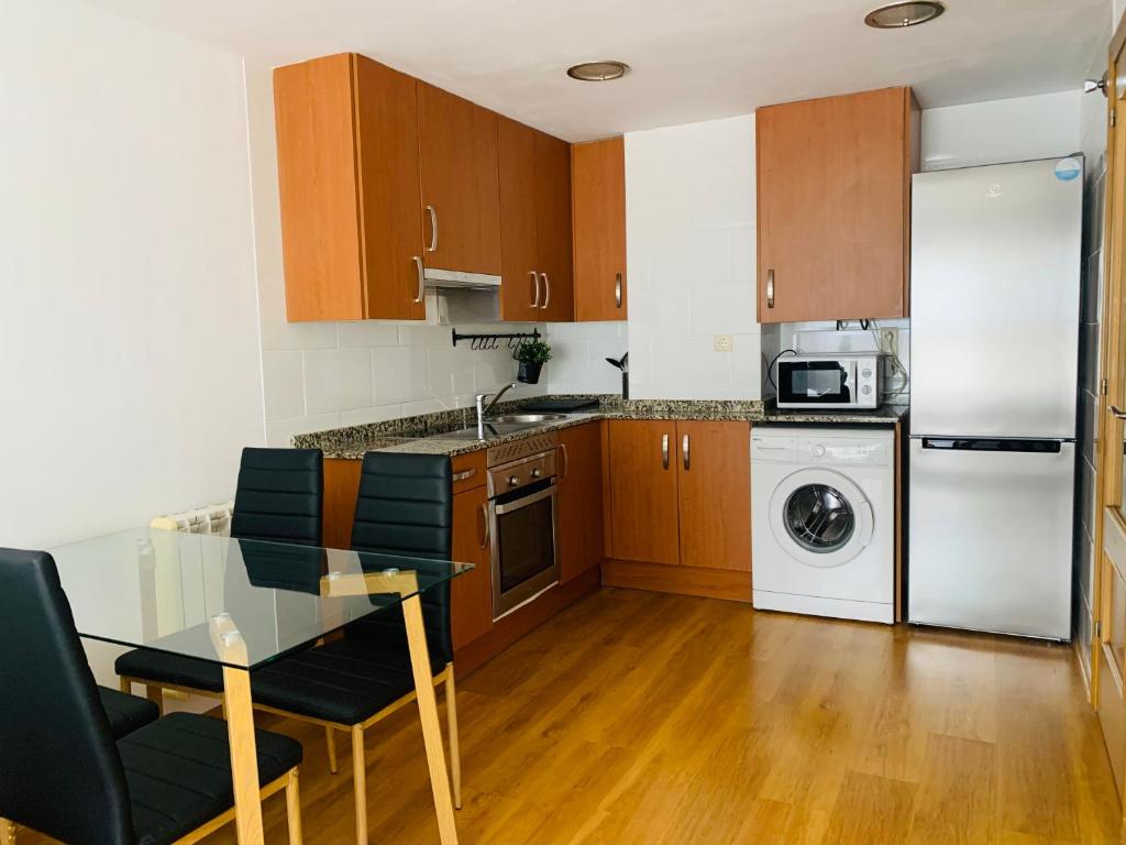 a kitchen with a glass table and a refrigerator at Apartamento Rio San Isidro 2 in Felechosa