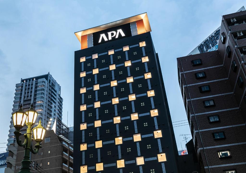 un edificio alto con un cartel de apfw en él en APA Hotel Namba-Shinsaibashi Nishi en Osaka
