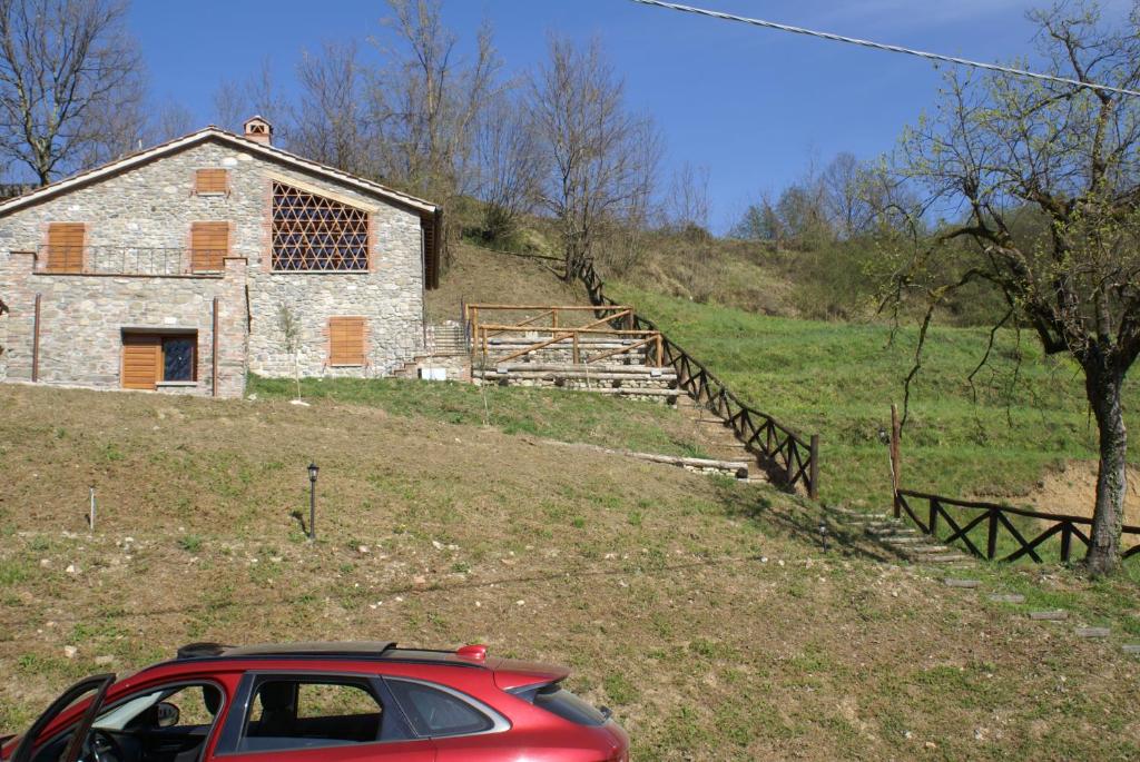 巴爾加的住宿－Tramonto Casa Barga Toscana ristrutturata 2021，停在石头建筑前面的红色汽车
