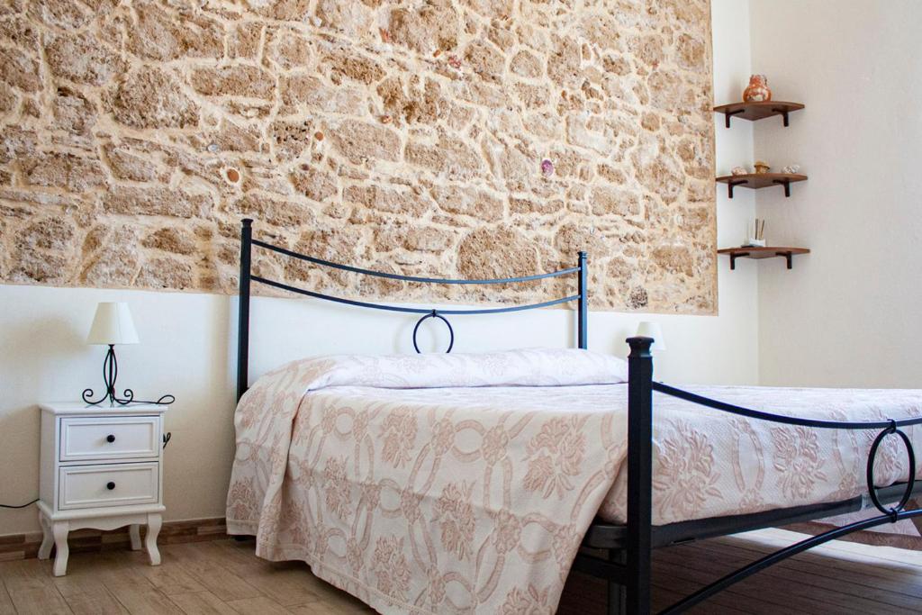 1 dormitorio con cama y pared de piedra en Poseidon Alghero, en Alghero