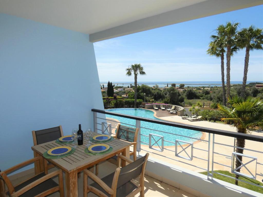 a balcony with a table and chairs and a swimming pool at Apartamento Phillipe in Odiáxere