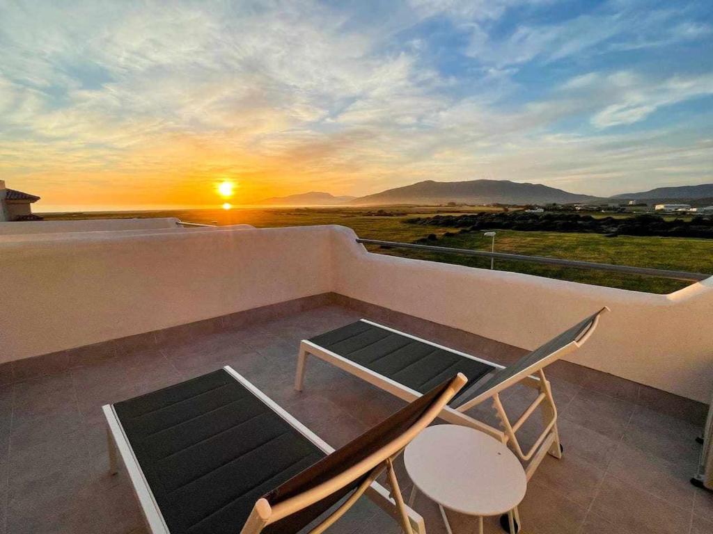 a balcony with a table and chairs and the sunset at Tarifa Beach Rentals Sunset in Tarifa