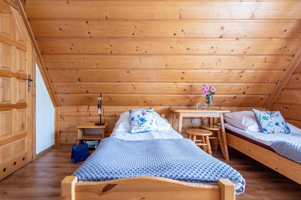 twee bedden in een kamer met een houten muur bij Pawlikówka 2 in Zakopane