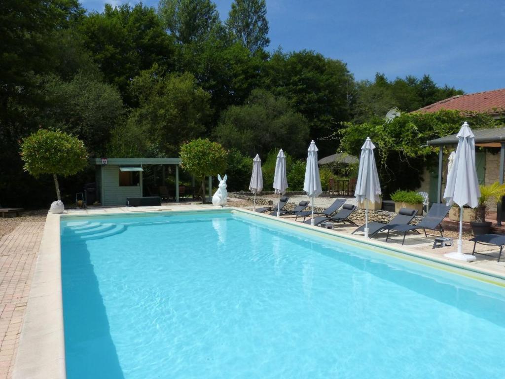 a swimming pool with chairs and umbrellas at La Vergne in Saint-Martin-des-Combes