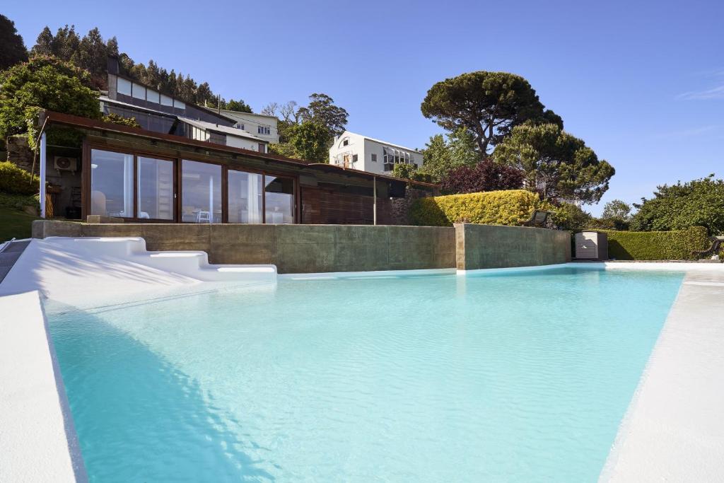 a swimming pool with blue water in front of a house at Apartamento con piscina y excelentes vistas in Ferrol