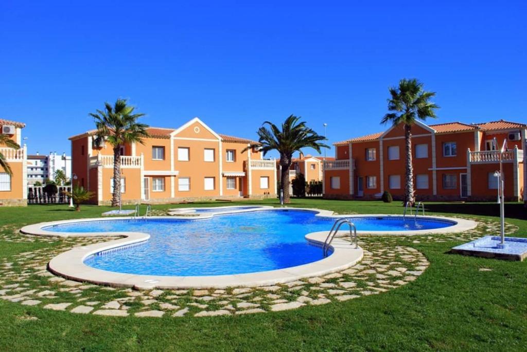 a large swimming pool with palm trees and houses at OLIVA NOVA GOLF BEACH & RESORT Club Sevilla V in Oliva