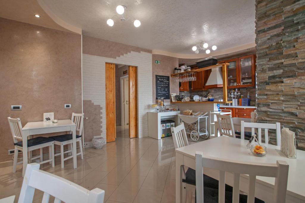 cocina y comedor con mesas y sillas blancas en Rogiual en Roma