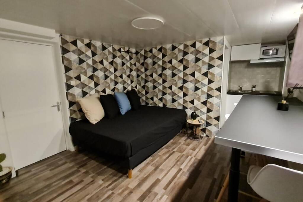 ein Wohnzimmer mit einer schwarzen Couch in einem Zimmer in der Unterkunft Halte Mignonne in Houldizy