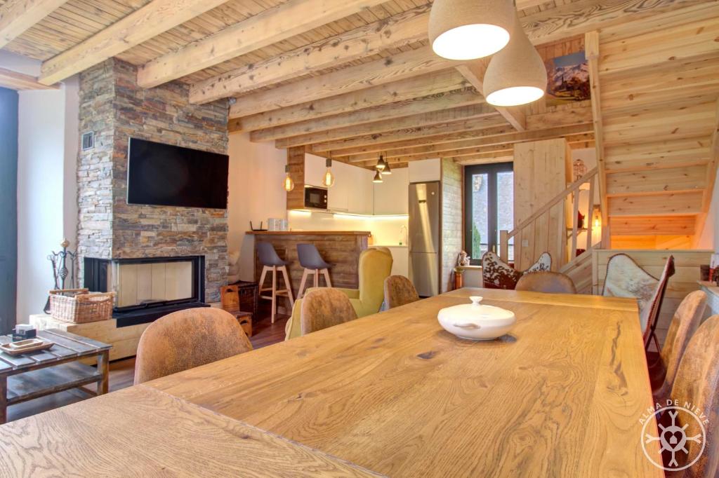 une salle à manger avec une table en bois et une cheminée dans l'établissement CASA ERA CUMA de Alma de Nieve, à Salardú