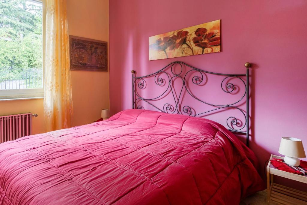 a pink bedroom with a bed with a red bedspread at At Armando's Home in Zafferana Etnea